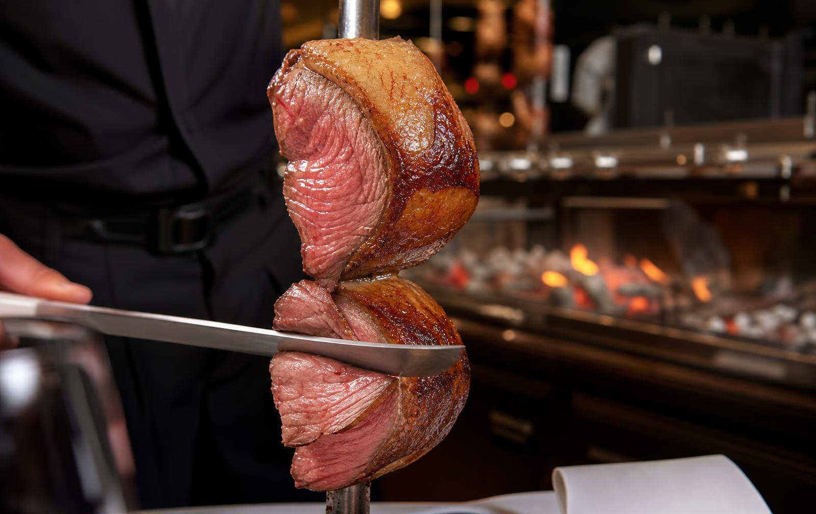Picanha fatiada no espeto sobre brasas